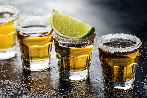 Tequila coctel de la bebida alcohol sabroso con limón y sal sobre fondo oscuro vibrante. Closeup. Horizontal. photo