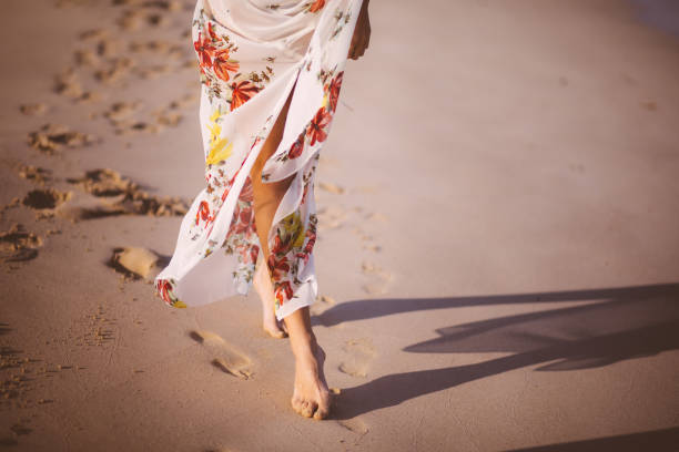 istock Young woman's legs walking barefoot at the beach 692858536