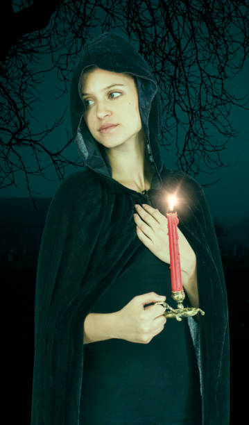 istock Widow witch in black hood with lit candle 692865418