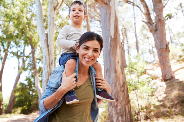 istock Son Riding On Mother's Shoulders On Countryside Walk 692870214