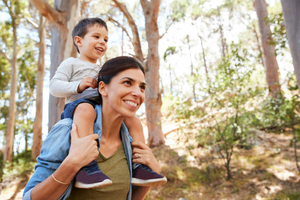 istock Son Riding On Mother's Shoulders On Countryside Walk 692872432