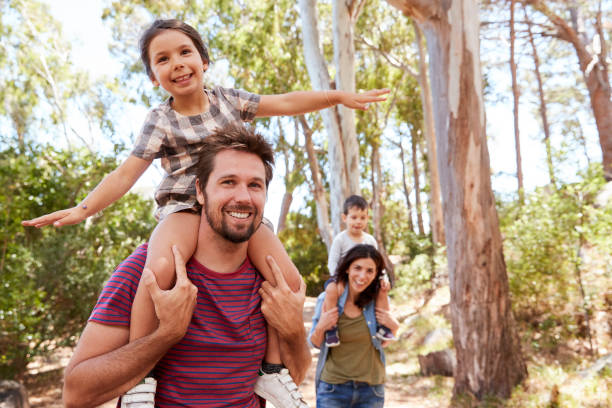 Children Riding On Parent's Shoulders On Countryside Walk Children Riding On Parent's Shoulders On Countryside Walk summer forest stock pictures, royalty-free photos & images