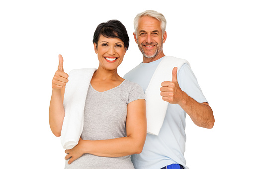 Portrait of a happy fit couple gesturing thumbs up over white background