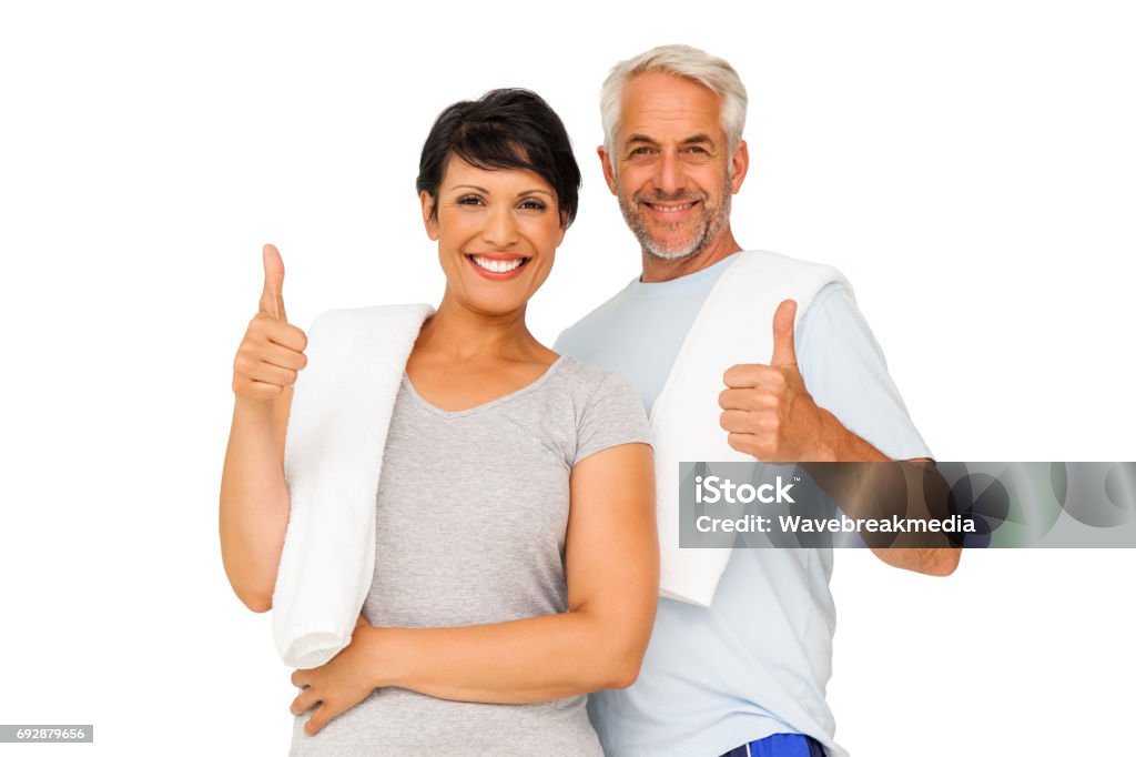 Portrait of a happy fit couple gesturing thumbs up Portrait of a happy fit couple gesturing thumbs up over white background Couple - Relationship Stock Photo