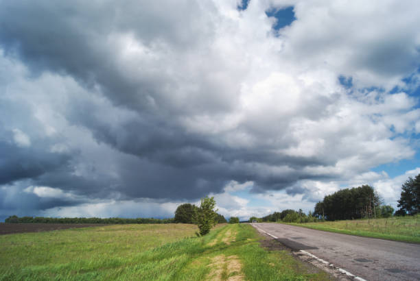 istock Road and green fields against a stormy sky 692880276