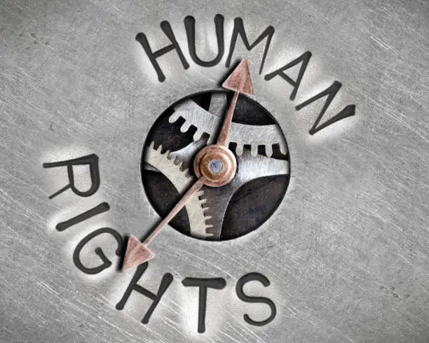 Macro photo of pointer and tooth wheel mechanism with HUMAN RIGHTS letters imprinted on metal surface