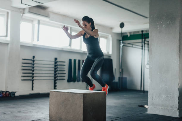 istock Fitness girl in mid-air doing box squats 692888662