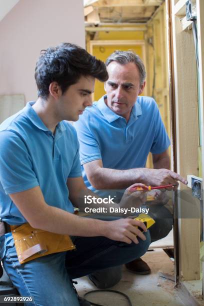 Electricista Con Aprendiz Trabajando En Nuevo Hogar Foto de stock y más banco de imágenes de Aprendiz