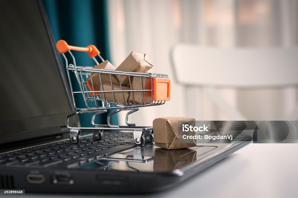 オンライン ショッピングの概念。ショッピング カート、小箱、机の上のノート パソコン - eコマースのロイヤリティフリーストックフォト
