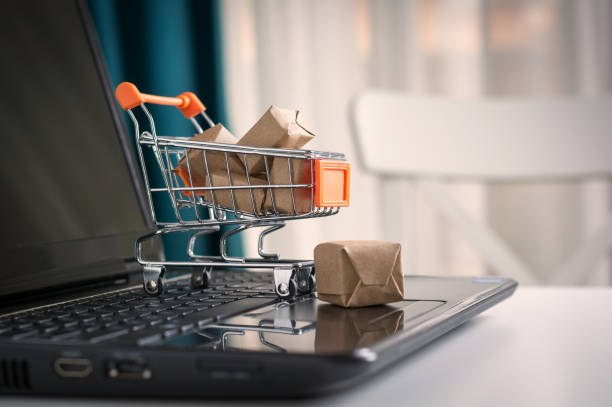Online shopping concept. Shopping cart, small boxes, laptop on the desk stock photo
