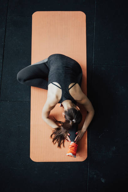 вид сверху йога женщина в голова к колену вперед согнуть позу - stretching yoga exercise mat women стоковые фото и изображения