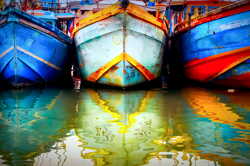 Multicolored old boat in the fishing port. Colored reflections in the water. Sri Lanka. Tangalle.