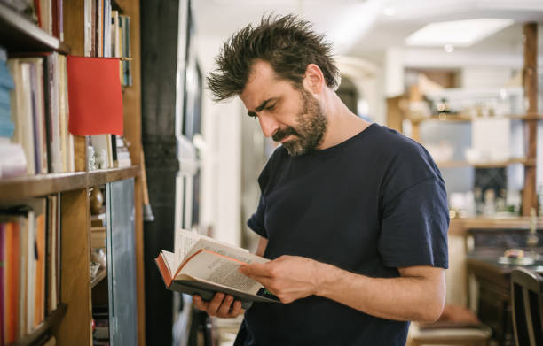 istock Curious man choosing book in his library at home 692907686