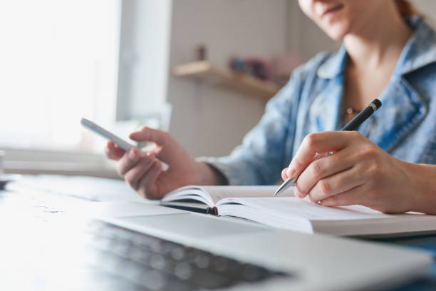 istock Person writing notes and working on the phone 692914992