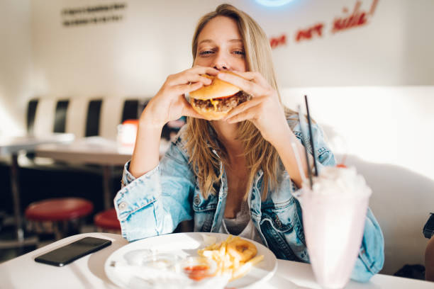 Food and drink Young woman eating burger in restaurant blended drink photos stock pictures, royalty-free photos & images