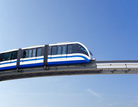 Monorail train moves on railway girder against background of blue sky