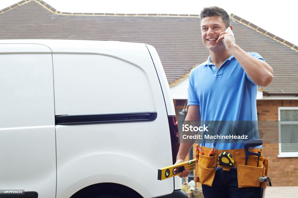 Builder With Van Talking On Mobile Phone Outside House Talking Stock Photo