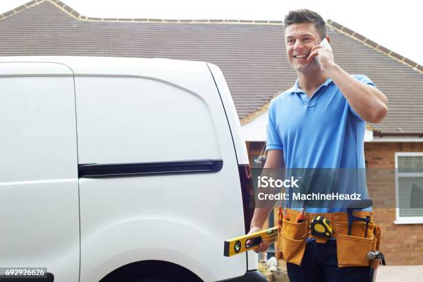 Builder With Van Talking On Mobile Phone Outside House Stock Photo - Download Image Now