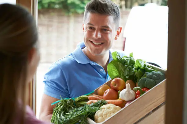 Man Making Home Delivery Of Organic Vegetable Box