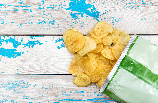 Potato chips scattered with packaging on the table. Top view.