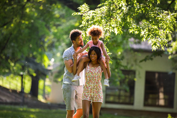 istock Mother carrying daughter on shoulders during walk in park 692931356