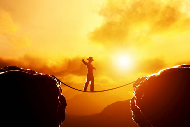 istock Man in hat walking, balancing on rope over mountains at sunset 692947918