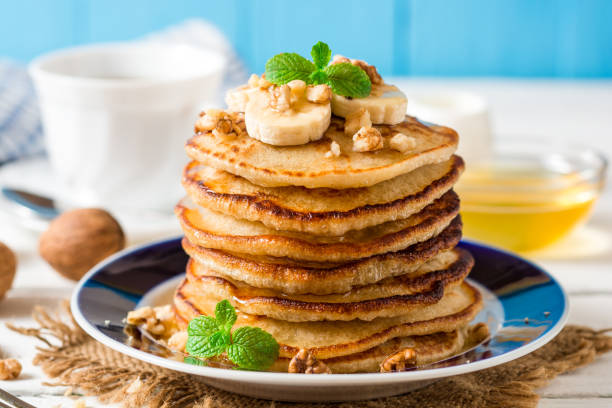 istock Pancakes with banana, honey, walnuts and mint on plate. 692948570