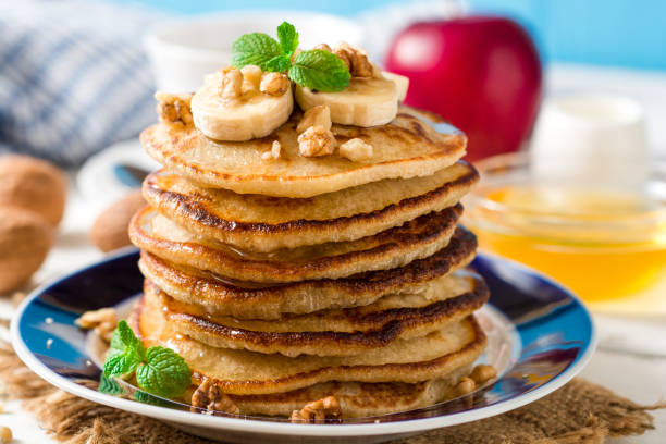 istock Pancakes with banana, honey, walnuts and mint on plate. 692951122