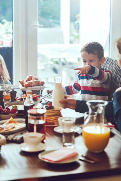 istock Young Family Having Breakfast with Eggs, Bacon, Yogurt with Fresh Fruits 692954348