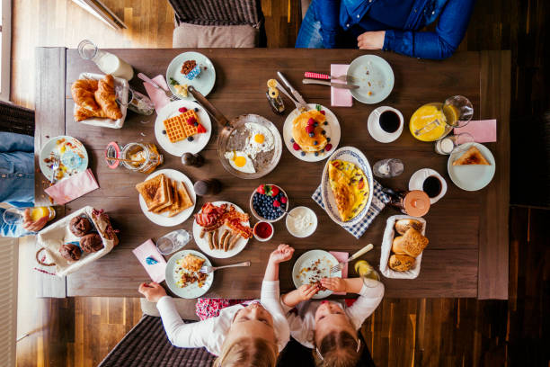 istock Young Family Having Breakfast with Eggs, Bacon, Yogurt with Fresh Fruits 692955404