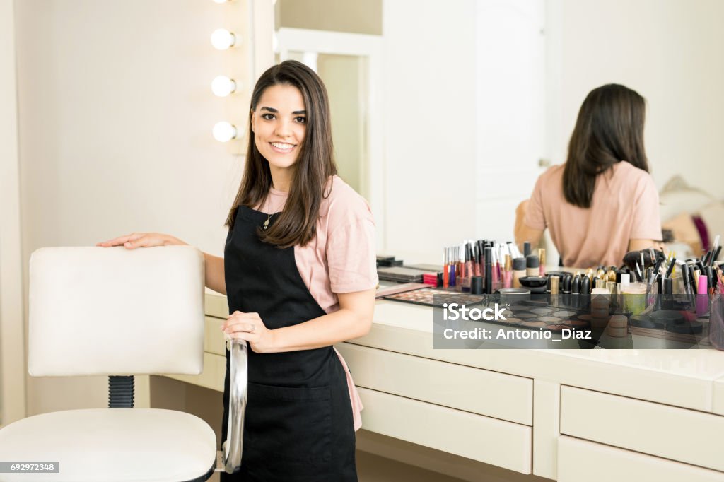 Pretty make-up artist in a beauty salon Gorgeous young business owner pulling up a chair and greeting customers into her beauty salon Business Stock Photo
