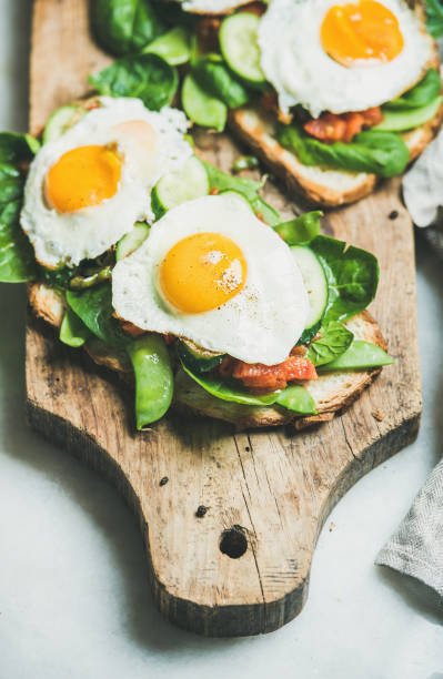 istock Healthy breakfast sandwiches on wooden board over grey background 692983906