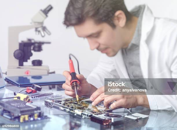 Young Energetic Male Tech Or Engineer Repairs Electronic Equipment Stock Photo - Download Image Now