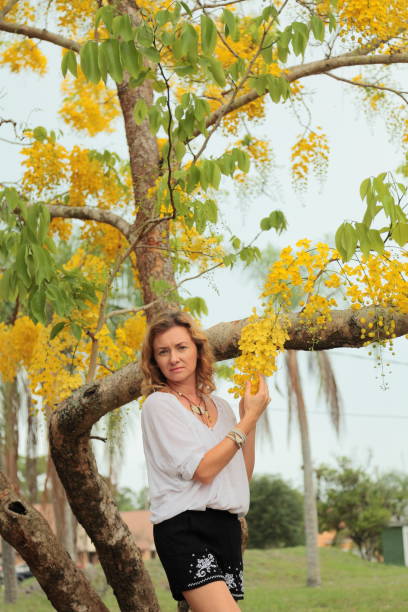 istock Young woman with yellow blooming Laburnum tree on the background. 692989606