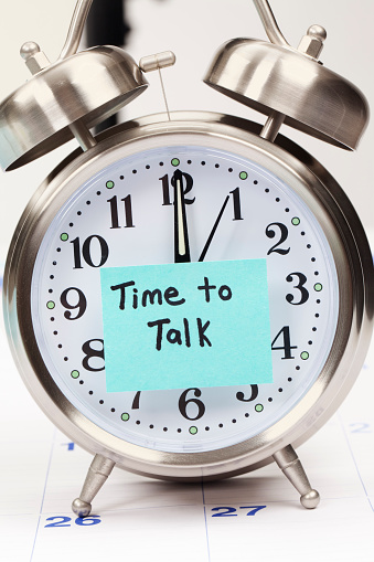 Time To Talk message on a sticky note stuck to the face of an alarm clock.