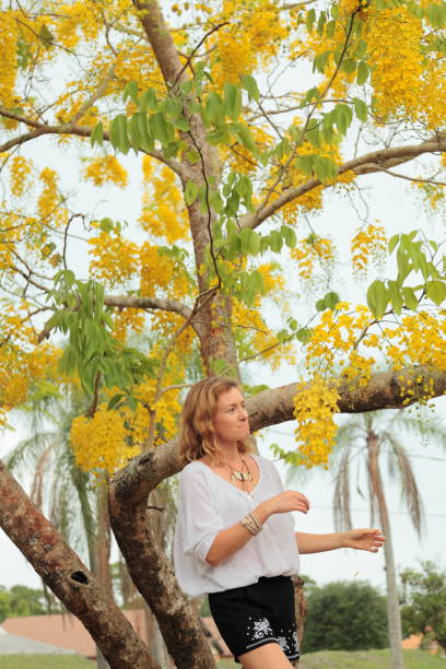 istock Young woman with yellow blooming Laburnum tree on the background. 693000360