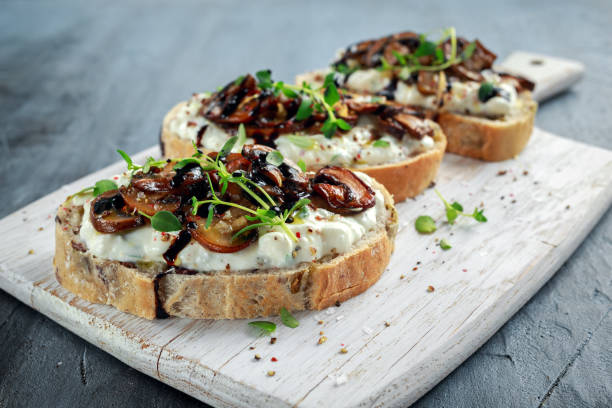 tostadas de setas ajo con queso ricotta cremoso de hierbas extendido - baked mushrooms fotografías e imágenes de stock