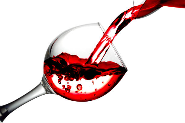 istock Red dry wine pours into a wineglass on a white background 693013920