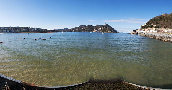 San Sebastian, Spain, 01/27/2017: people paddling in the waters of the Bay of Biscay in Donostia-San Sebastian at the famous beach of La Concha, considered one of the best city beaches in Europe