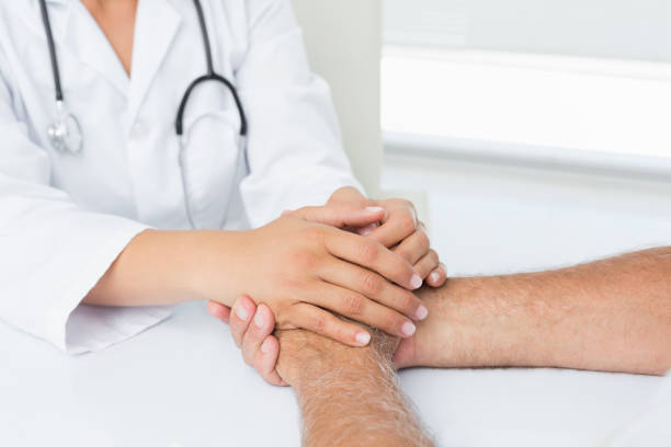 istock Close-up mid section of a doctor holding patients hands 693020428