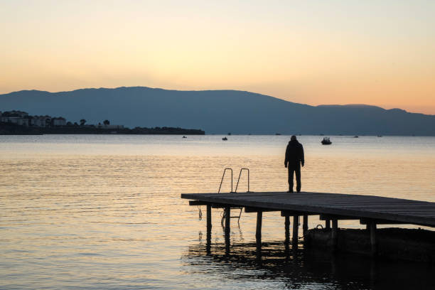 istock Lonely man is standing in the pier while sunset 693020782