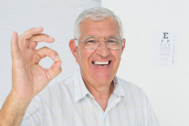 istock Smiling senior man gesturing ok with eye chart in background 693040080
