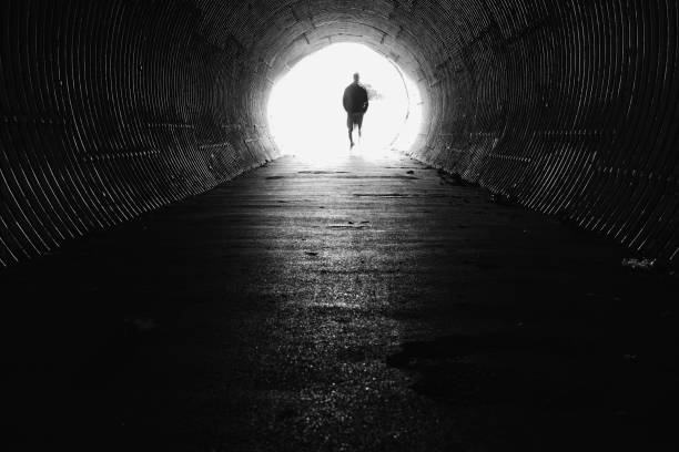 Light at the end of the tunnel with silhouette of man Dark tunnel with light end. Silhouette man on the end. light at the end of the tunnel photos stock pictures, royalty-free photos & images