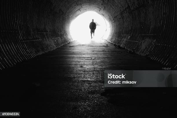 Light At The End Of The Tunnel With Silhouette Of Man Stock Photo - Download Image Now