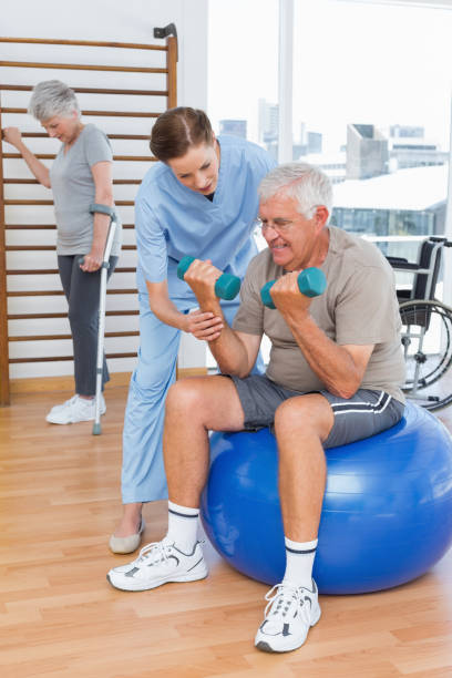 istock Therapist assisting senior man with dumbbells 693041164