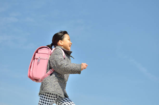 ragazza che corre nel cielo blu (borsa della scuola) - randoseru foto e immagini stock