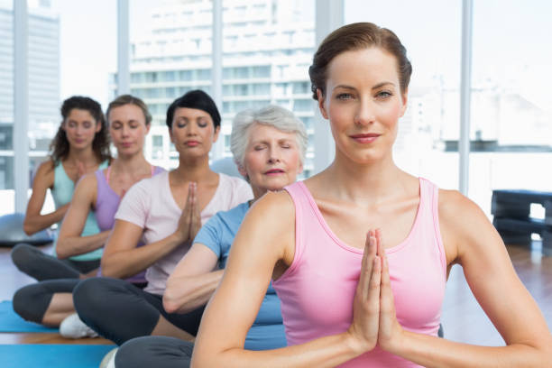 istock Class sitting with joined hands in row at yoga class 693054478