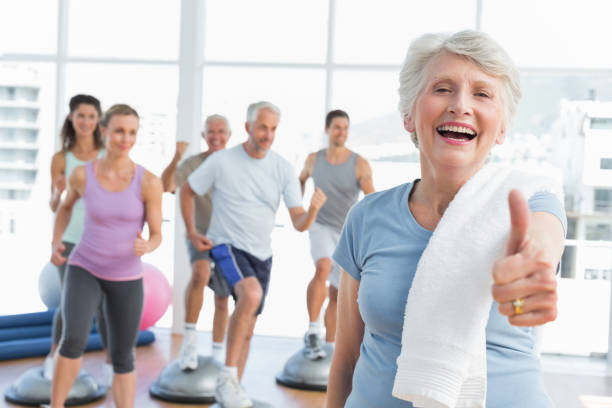 istock Senior woman gesturing thumbs up with people exercising 693067192