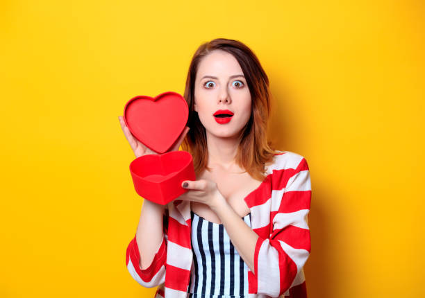 istock Woman with heart shape box on yellow background 693071460