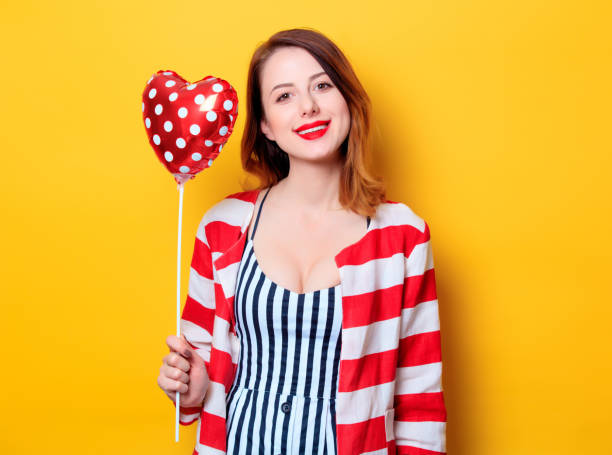 istock Woman with heart shape toy on yellow background 693071464